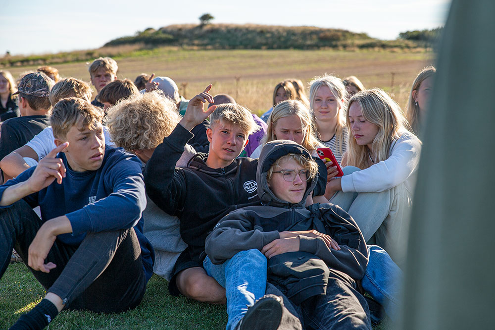 Elever sidder samlet udenfor på Venø Efterskole og viser fællesskabet i hverdagen på skolen.