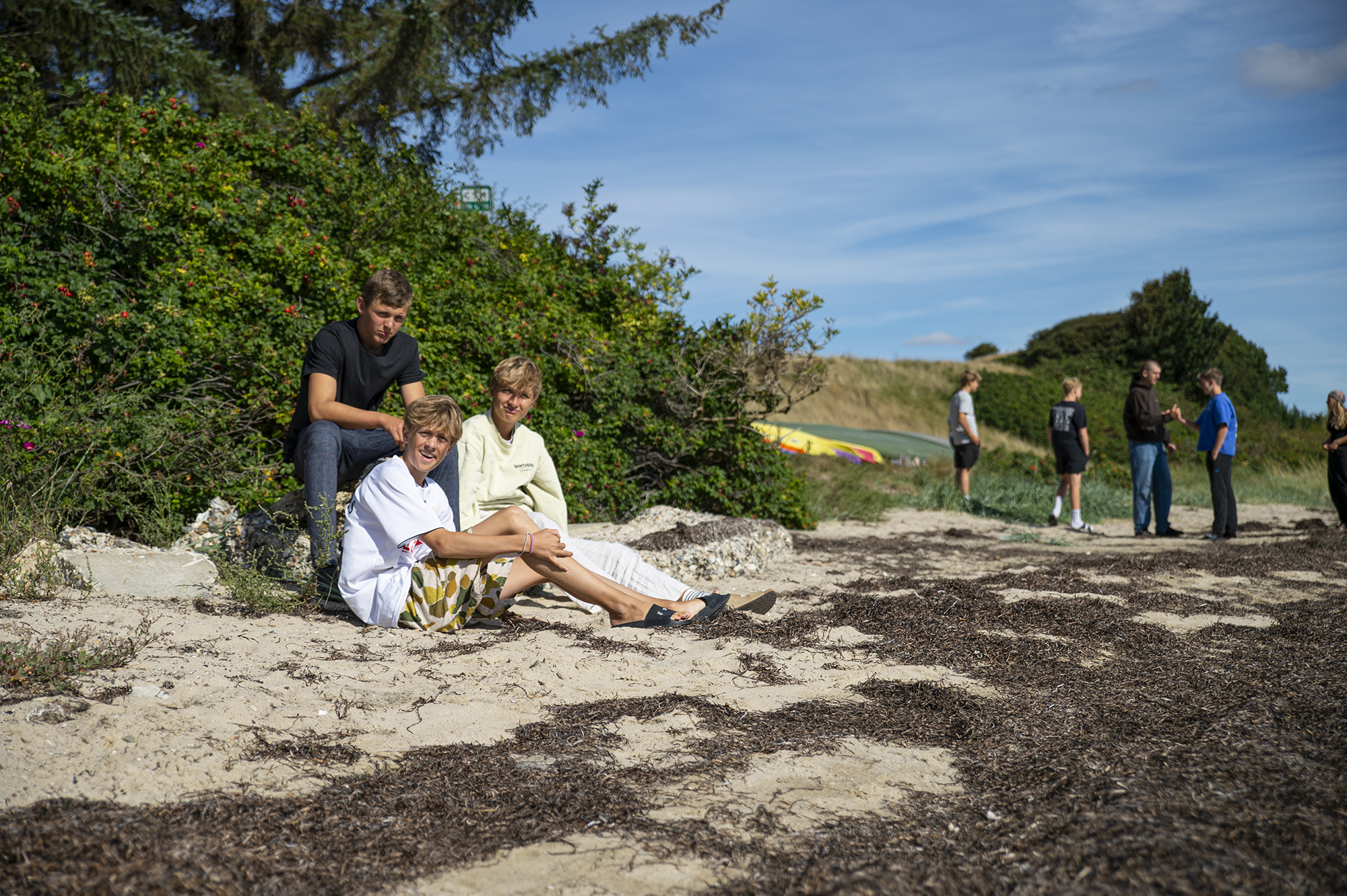 Elever nyder fællesskabet ved stranden på Venø Efterskole med Limfjorden i baggrunden.