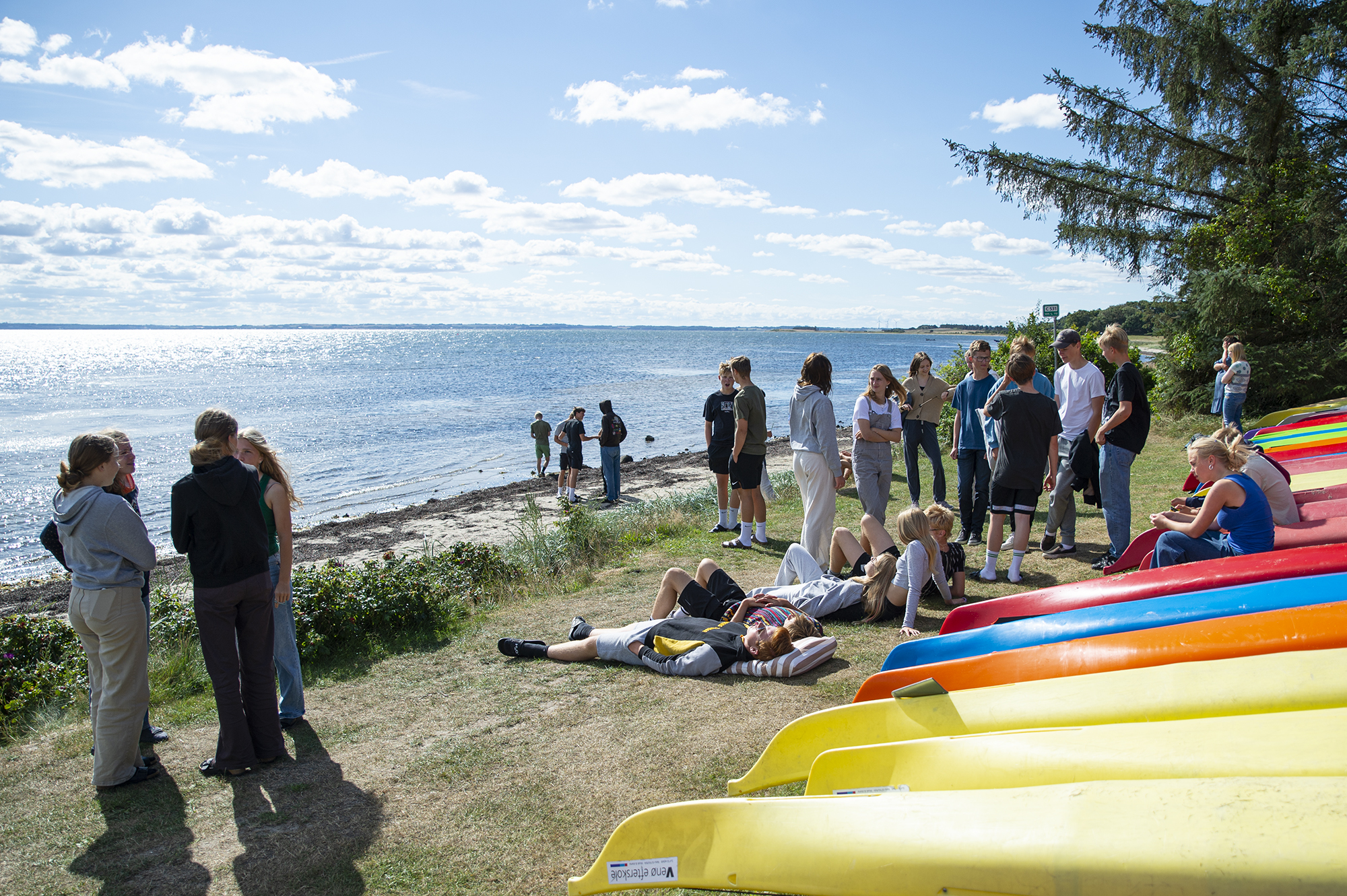 Elever samles ved stranden på Venø Efterskole med udsigt over Limfjorden og skolens kajakker.