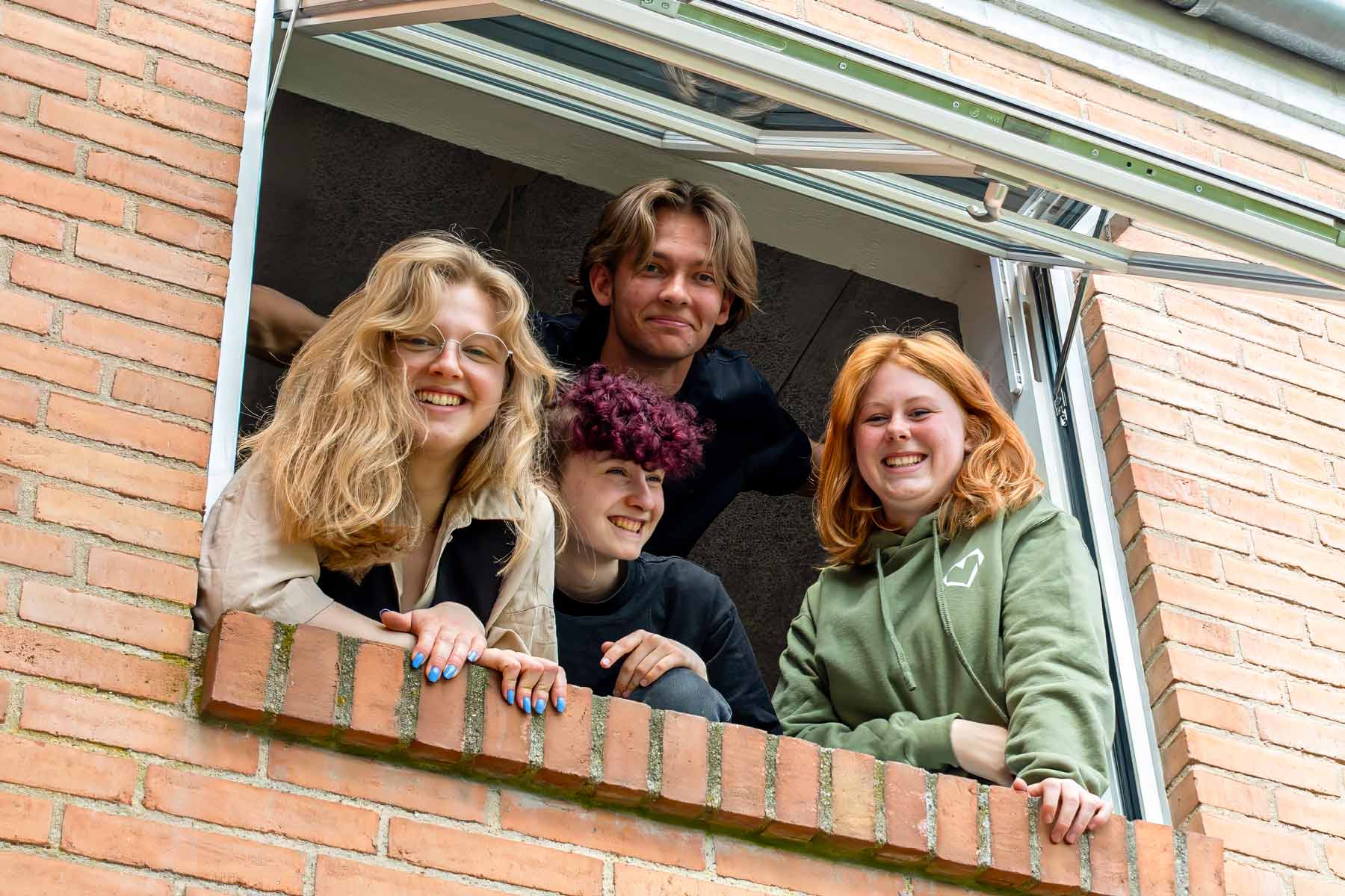 Elever smiler og kigger ud ad et vindue på Venø Efterskole ved Limfjorden.