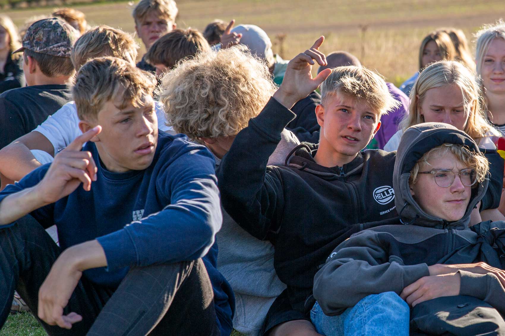Elever sidder samlet udenfor på Venø Efterskole og viser fællesskabet i hverdagen på skolen.
